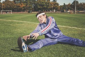 girl struggling to stretch in the park